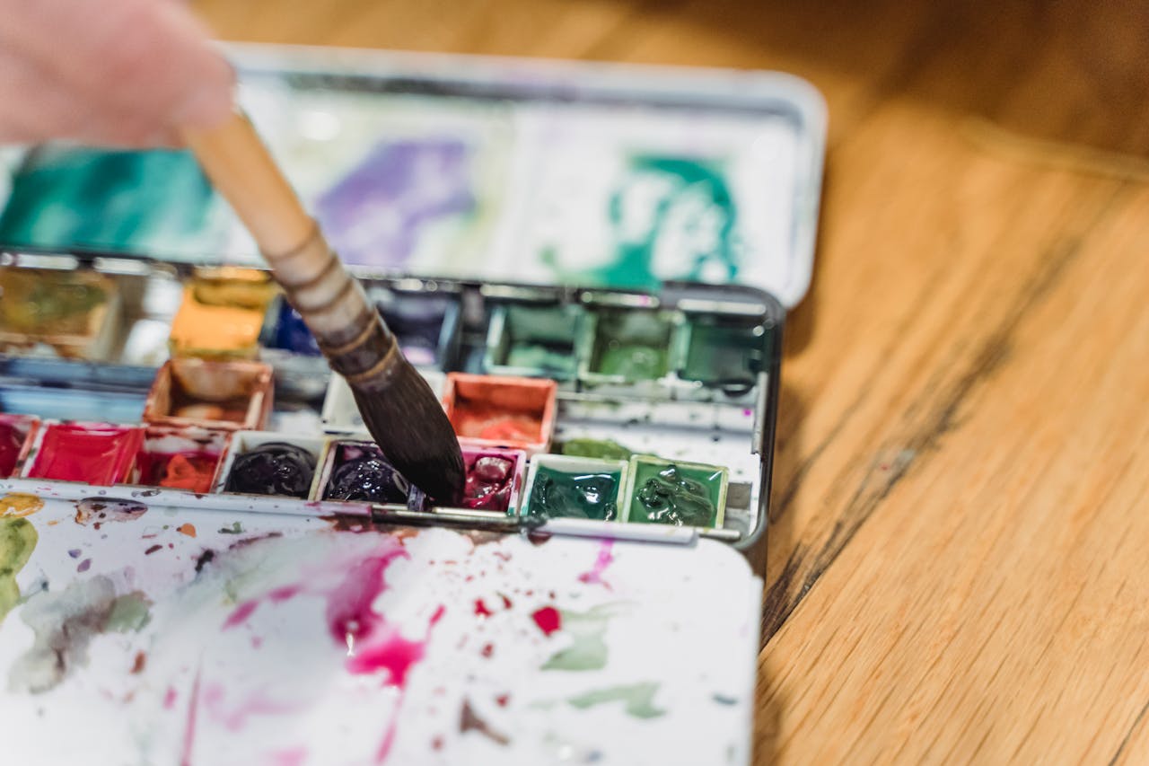 Close-up of a watercolor palette with a paintbrush, showcasing vibrant colors and artistic creativity.